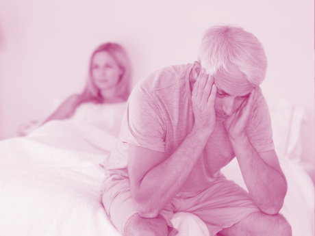 older couple sitting in bed, disappointed 