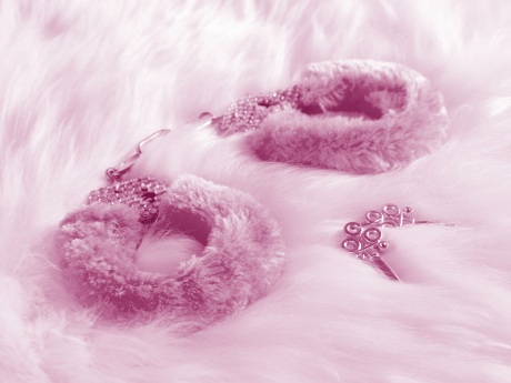 pink fuzzy handcuff on white fluffy blanket 