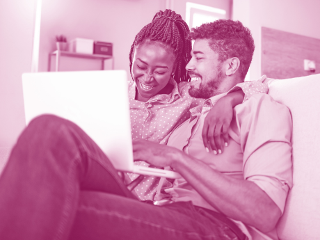 two people cuddling as they smile looking at laptop 