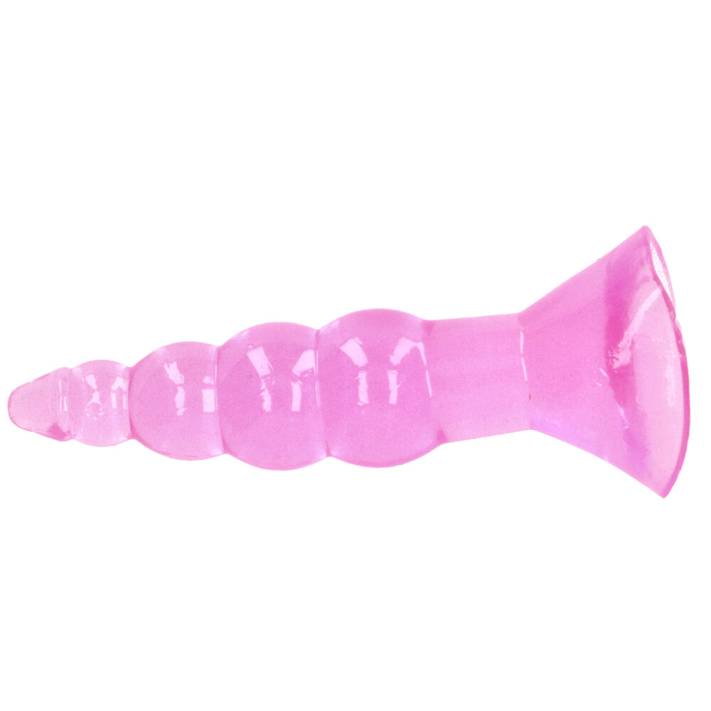 Pink beaded butt plug with suction-cup base and tapered tip lying on its side.