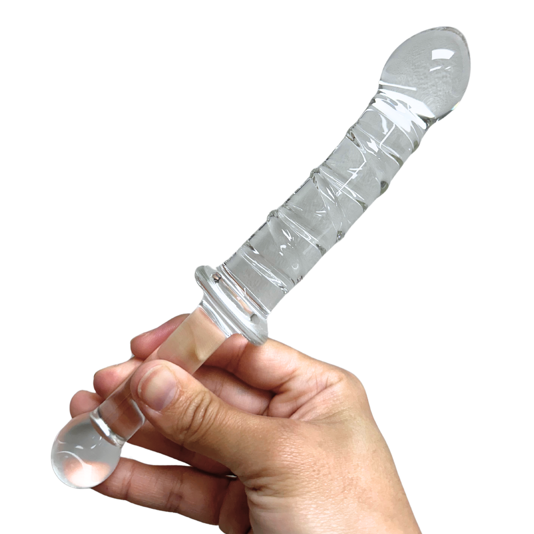 A hand holding the glass dildo from the handle