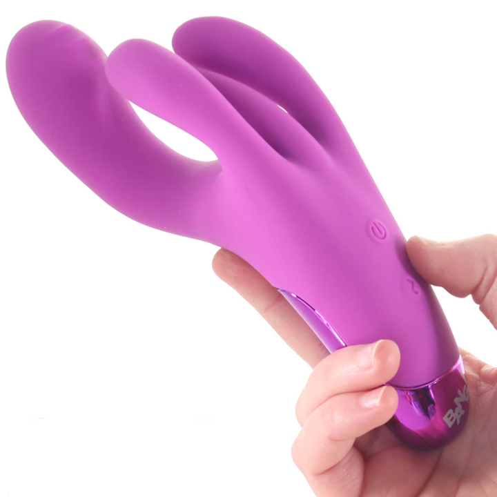 A hand holding the purple BANG! Triple Rabbit Silicone Vibrator.